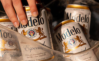 person pulling a modelo out of an ice bowl